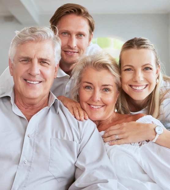 Smiling multi-generational family posing together in bright, modern dental office setting.
