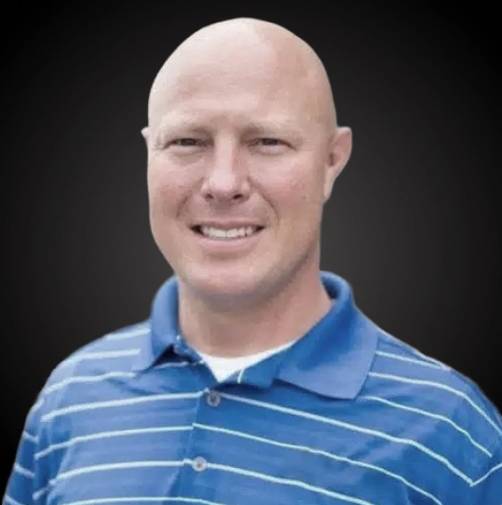 Professional headshot of a man in blue striped polo shirt against dark background for dental practice.
