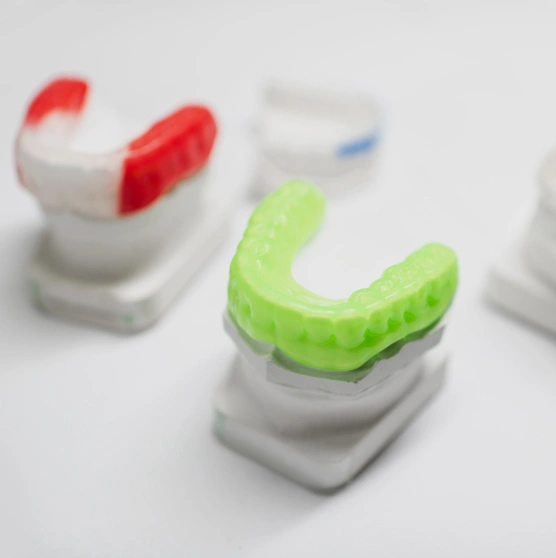 Colorful orthodontic aligners displayed on white dental models showcasing teeth straightening treatment options.