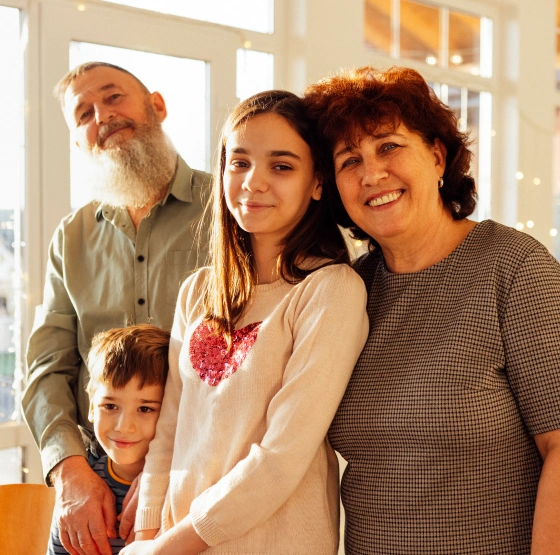 Multi-generational family smiling together in bright, modern home interior setting.