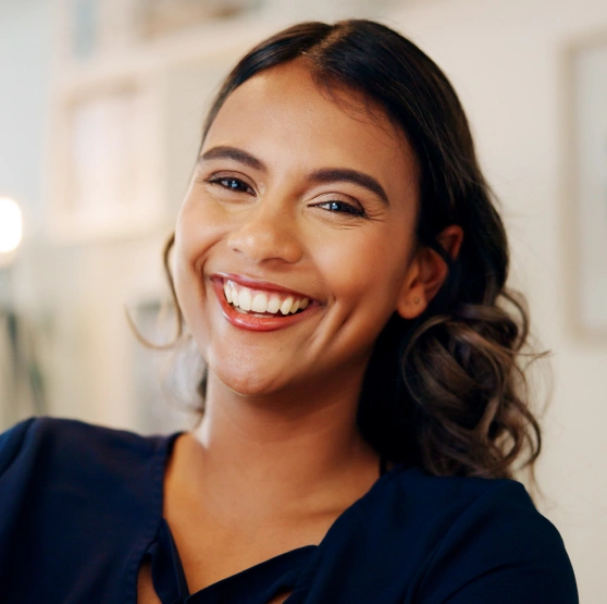 Smiling woman in dark scrubs in modern dental office setting