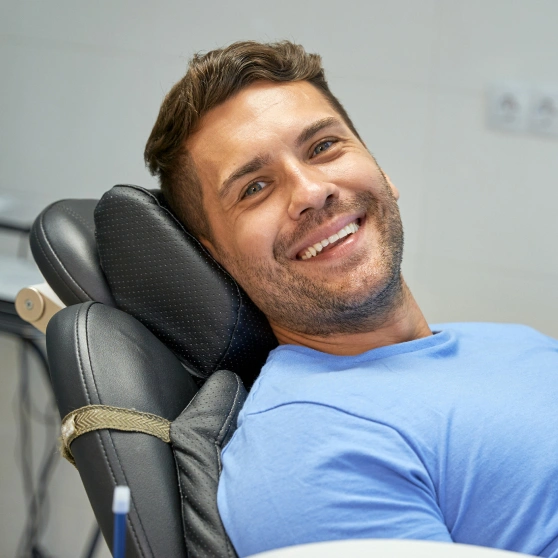 Smiling man in blue shirt relaxing in dental chair at modern dentistry office