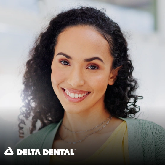 Smiling woman in dental office setting with Delta Dental branding visible.