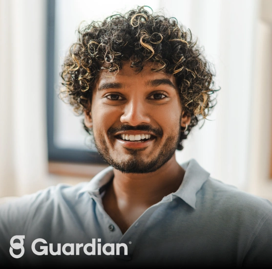 Smiling man with curly hair in light blue shirt, professional dental office portrait