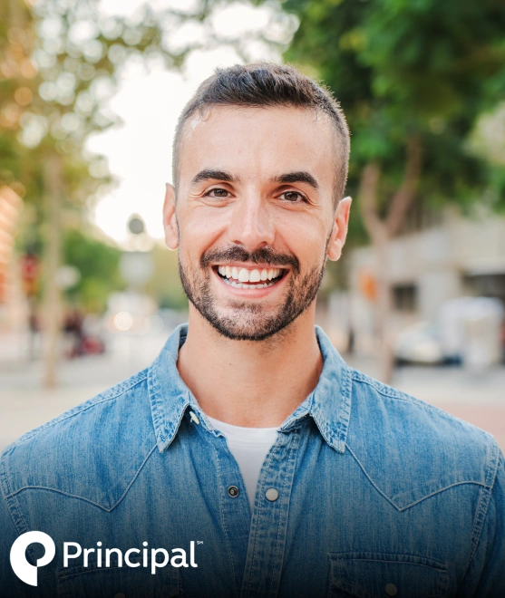 Smiling male dentist in denim shirt outdoors with blurred residential background.